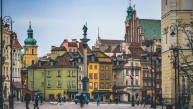 مشهد بانورامي لساحة مدينة وارسو القديمة يظهر المباني الملونة ذات الطراز الكلاسيكي والساحة العامة، يمثل نموذجاً عالمياً لإعادة الإعمار والحفاظ على الذاكرة المكانية