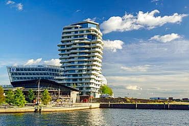 تصميم برج 'ماركو بولو' (Marco Polo Tower) المستدام في هامبورغ، حيث تظهر طوابقه المتداخلة والمنحنية التي تعمل كمظلات شمسية طبيعية لكل طابق، مما يقلل الحاجة للتبريد الميكانيكي ويجسد مفهوم الاستدامة من خلال التشكيل المعماري الذكي.