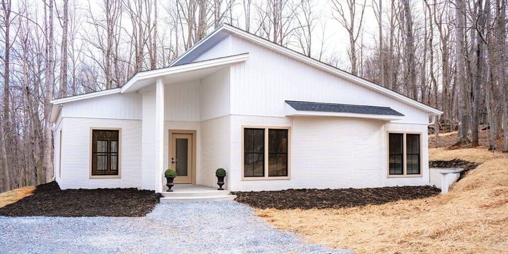 منظور خارجي لمنزل ريفي أبيض في ولاية فيرجينيا، وهو أول منزل يتم تسليمه ضمن مشروع Project Virginia، مشيد بـ تقنية الطباعة 3D لتوفير حلول إسكان ميسورة التكلفة بالتعاون مع "Habitat for Humanity".