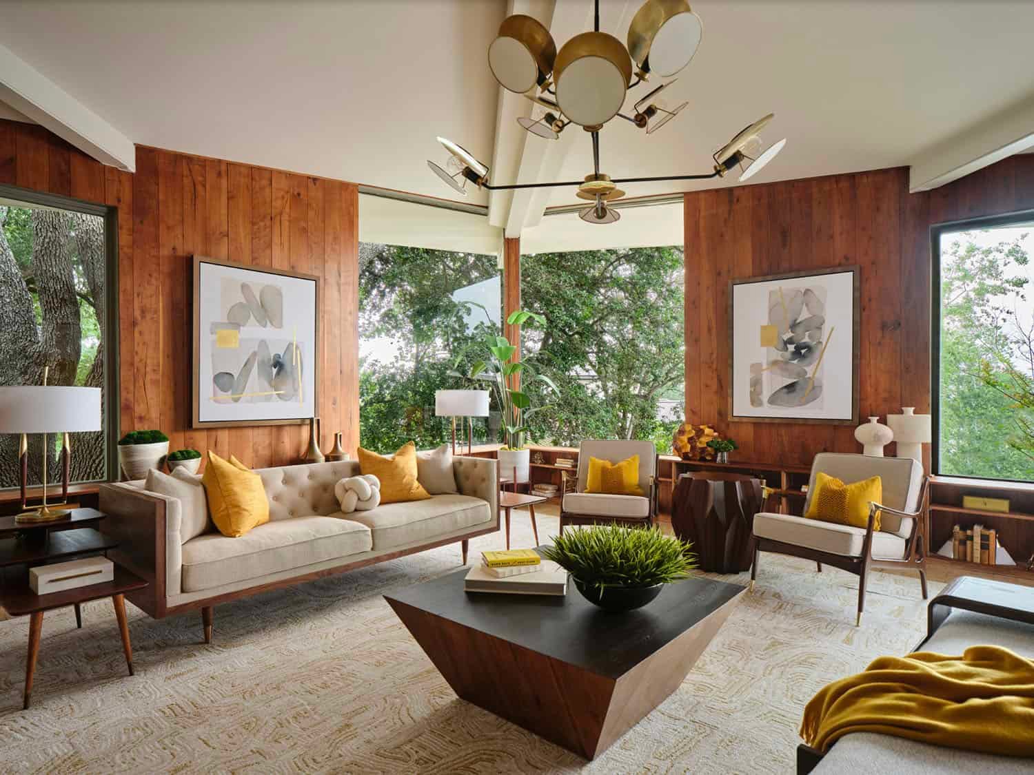 فراغ معيشة يجسد طراز Mid-Century Modern بكسوة جدران خشبية دافئة، أثاث بأرجل مدببة (Tapered Legs)، وثريا أيقونية، تطل على مساحات خضراء عبر نوافذ واسعة.
