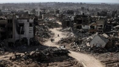 مشهد بانورامي لشارع مدمر في غزة، حيث تحول النسيج الحضري إلى تلال من ركام وأنقاض الرمادية التي تغلق الأفق العمراني.،