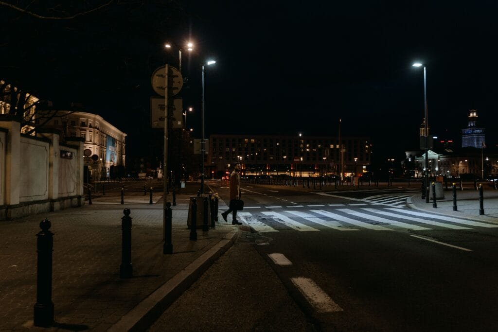 ممر مشاة ليلي في شارع حضري يعتمد على نظام إضاءة تكيفي  لتعديل شدة التوهج تلقائياً بناءً على الحركة الفعيلة وتوفير استهلاك الطاقة